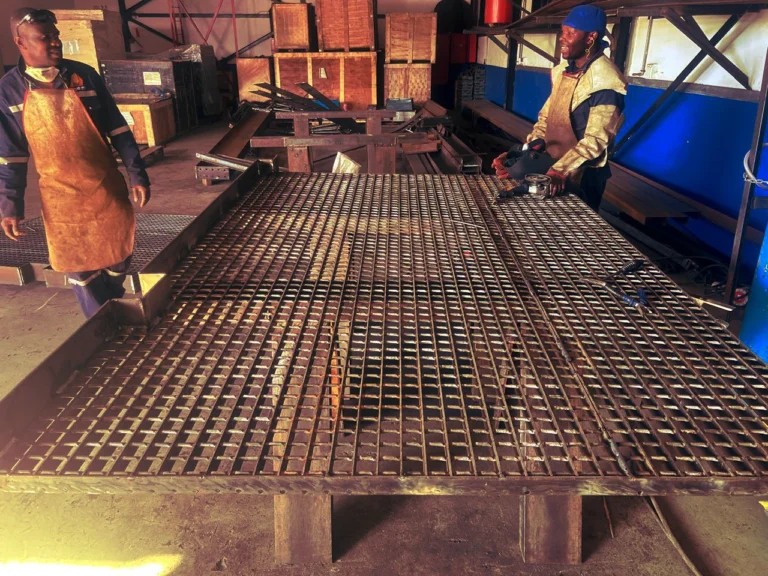Workers assembling a steel structure with a forklift at a construction site.
